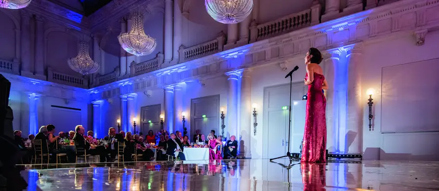 Sängerin im roten Kleid auf einer spiegelnden Bühne im Festsaal